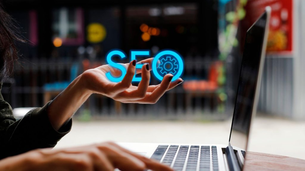 woman in front of laptop holding the letters SEO in her hands.