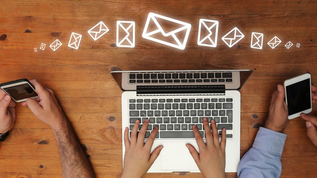 Business professionals checking email on a laptop and phones.