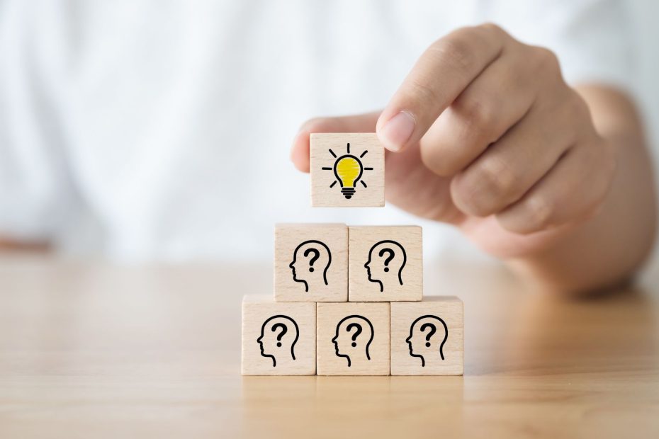 blocks stacked with peoples heads and a question marks with a light bulb at top.