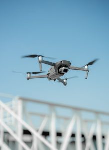 FAA Part 107 certified DJI Mavic 2 drone in flight against clear blue sky over construction – YellowHammer IT drone services Baldwin County Alabama