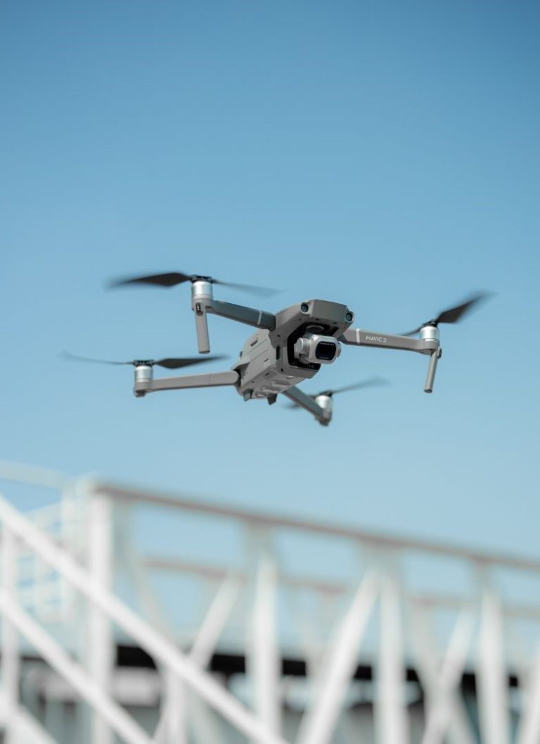 FAA Part 107 certified DJI Mavic 2 drone in flight against clear blue sky over construction – YellowHammer IT drone services Baldwin County Alabama