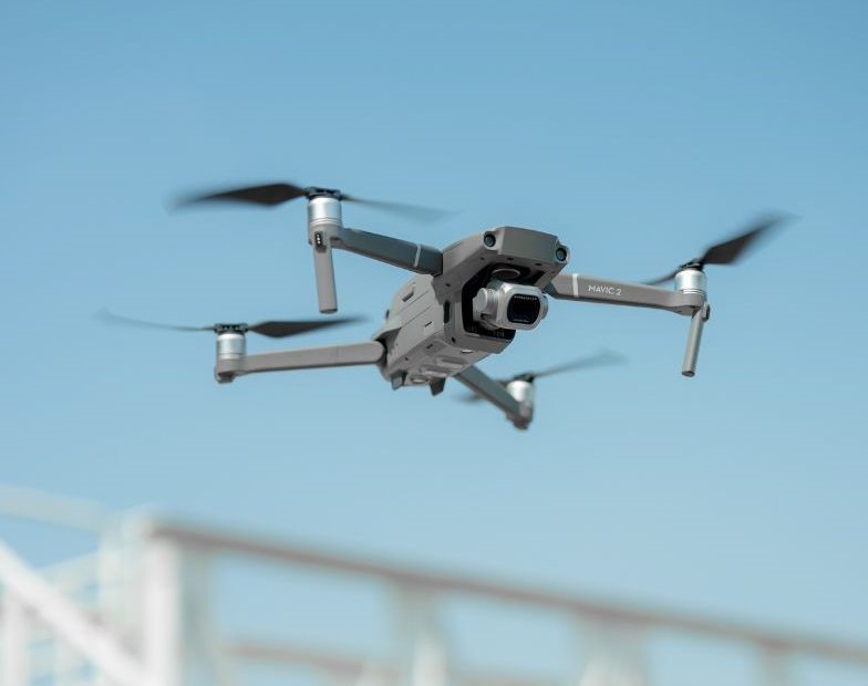 FAA Part 107 certified DJI Mavic 2 drone in flight against clear blue sky over construction – YellowHammer IT drone services Baldwin County Alabama